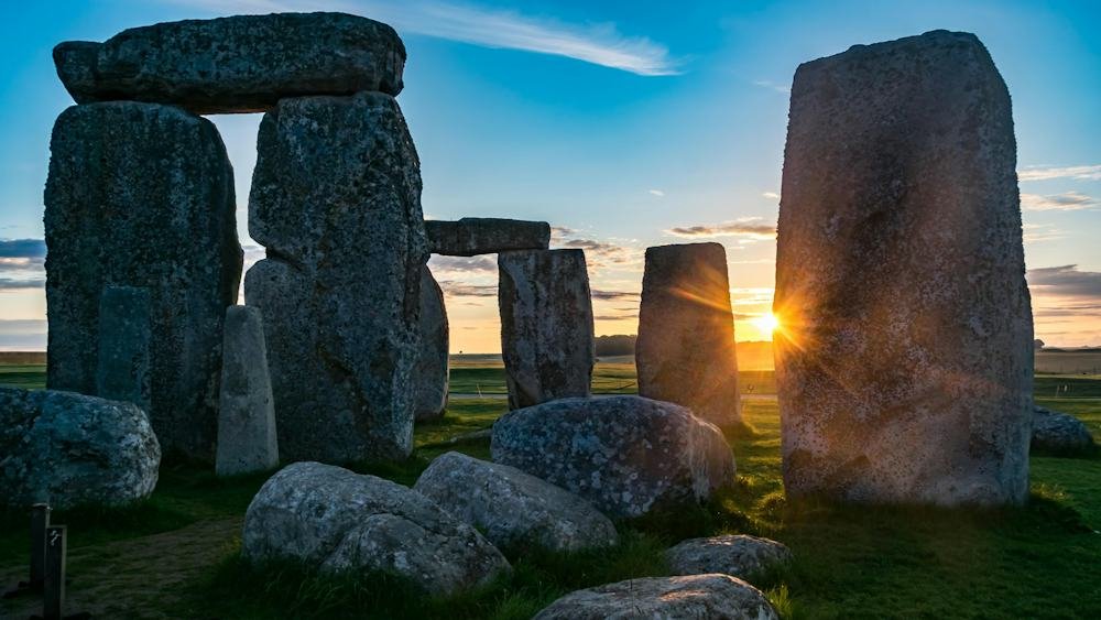 Sun setting behind the ancient stones of Stonehenge, a popular historic day trip from London