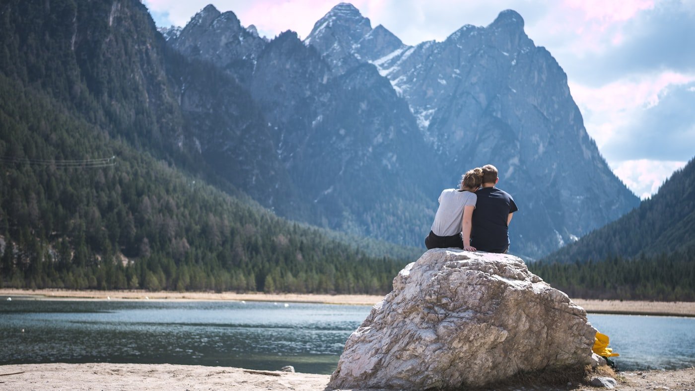 Couple sitting on a rock looking out over a lake during a peaceful mountain retreat getaway