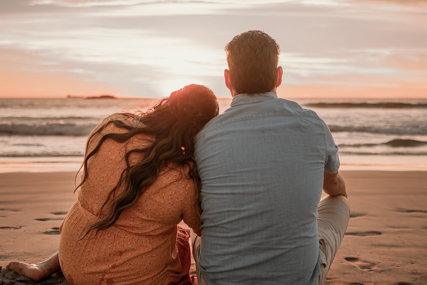 Couple sitting on the beach watching a romantic sunset during their honeymoon