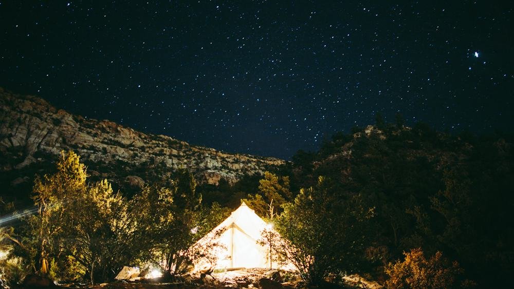 Glamping tent lit up at night under the stars in the mountains, near Colorado City, USA